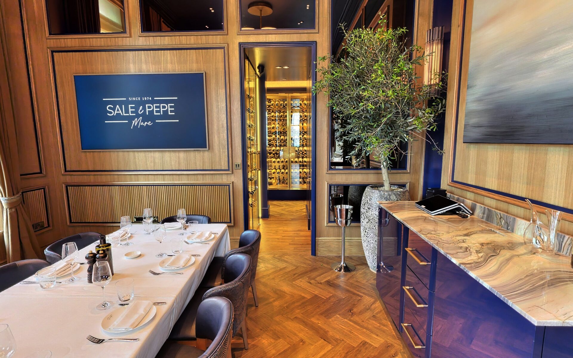 A private dining room at Sale e Pepe Mare with the illuminated Sale e Pepe Mare crest, set table and wine display