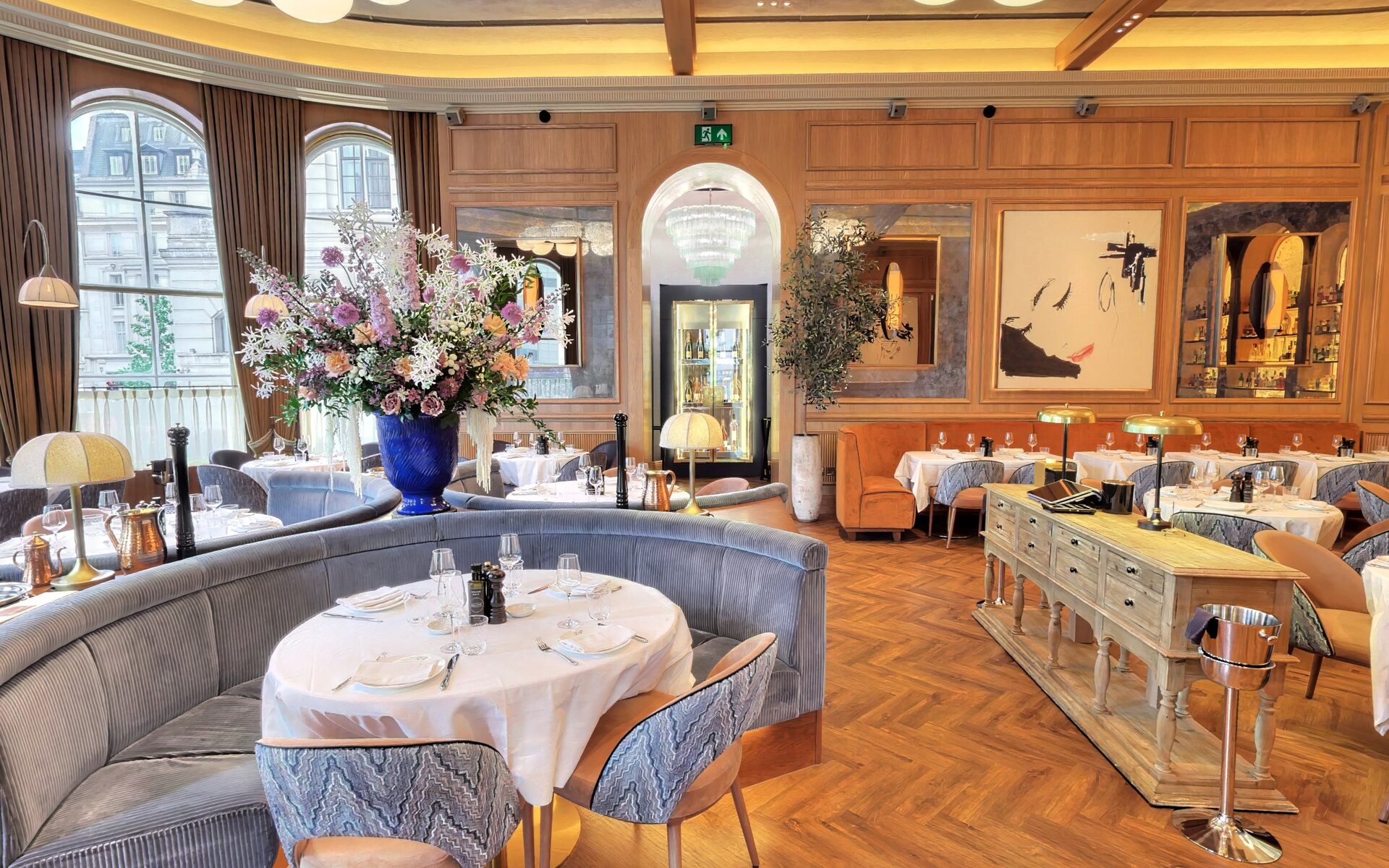 The grand dining room with a tall floral centrepiece, curved velvet banquette and chandelier