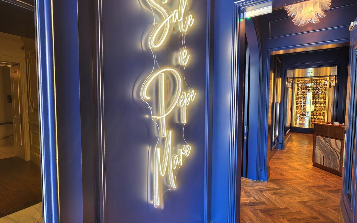 The neon Sale e Pepe Mare sign glowing on the deep navy entrance wall